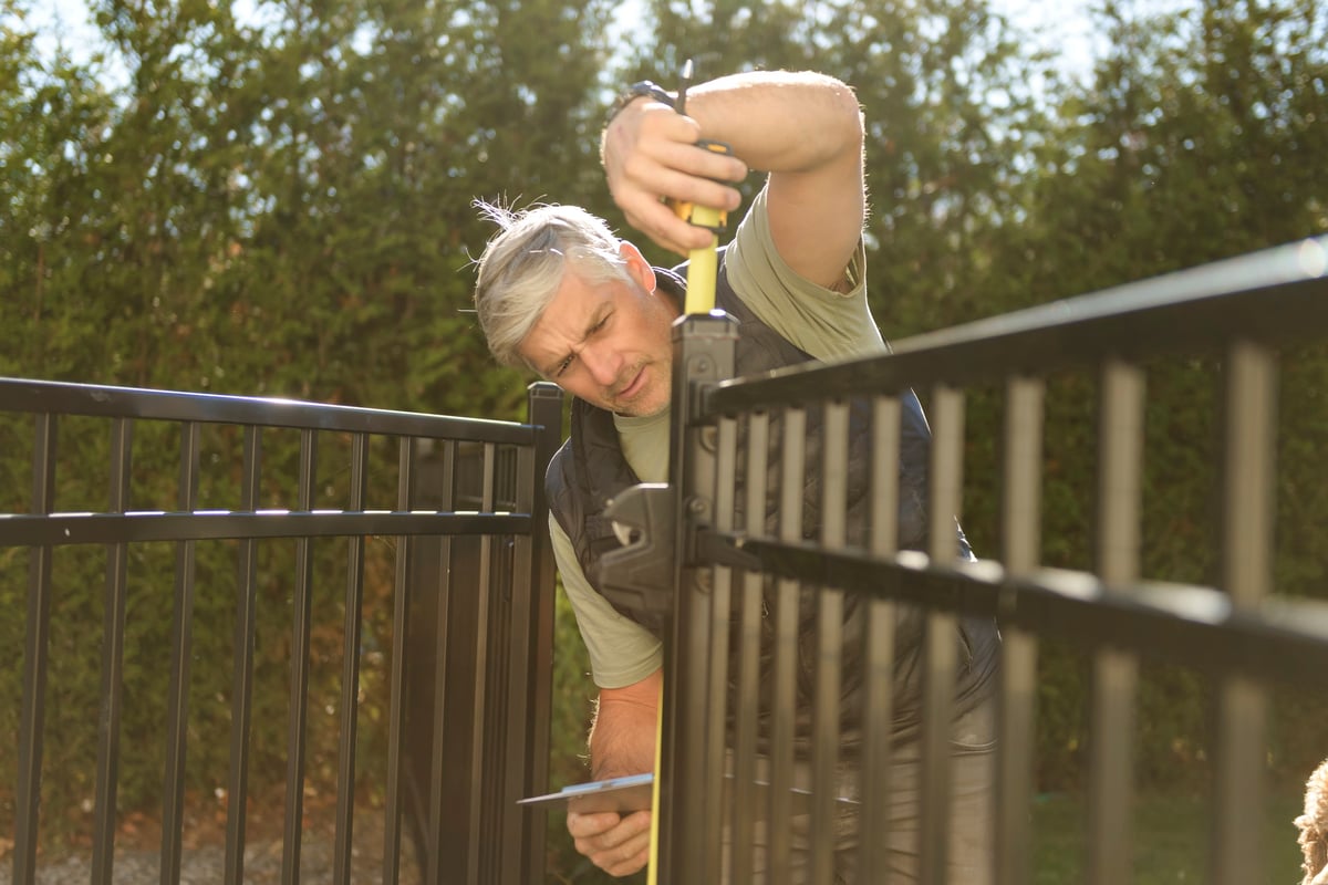 Workers measuring and inspecting a wooden fence installation
