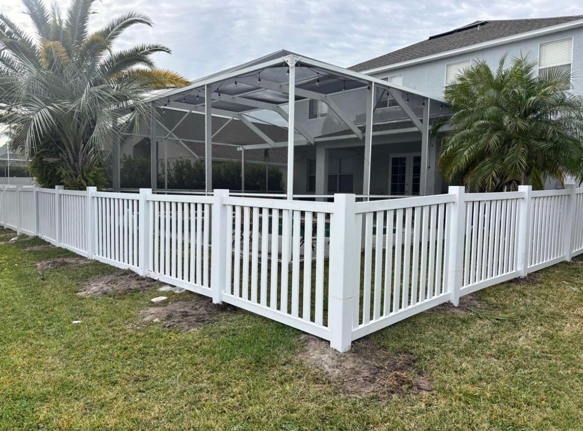 White screened-in patio with railing surrounding a residential home with palm trees and green lawn